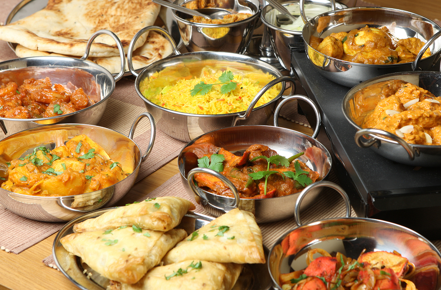 Selection of Indian food including curries, rice, samosas and na