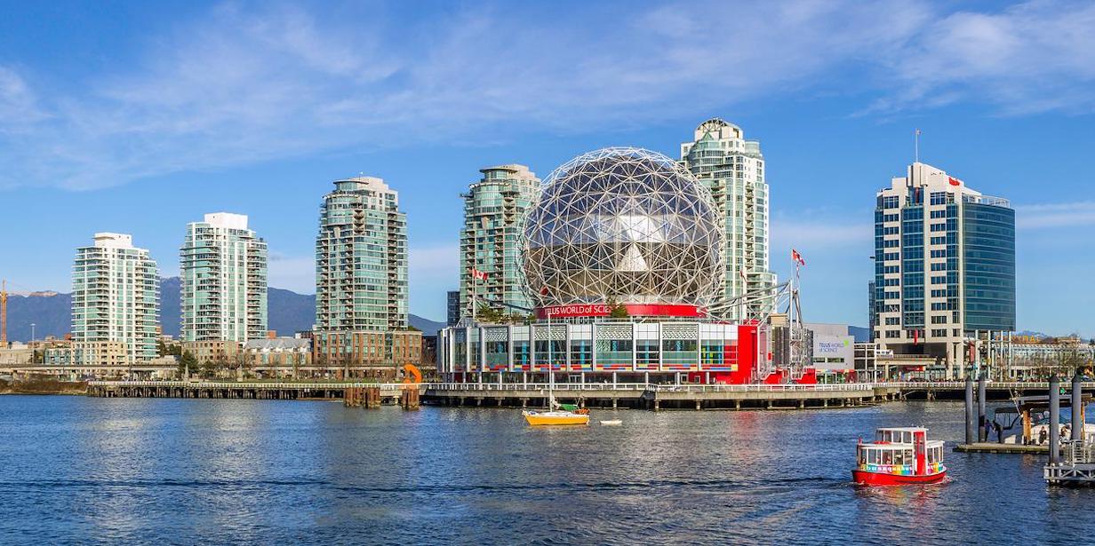 An image of the Vancouver, Canada cityscape by the sea on a bright sunny day which include the cities Science World dome.